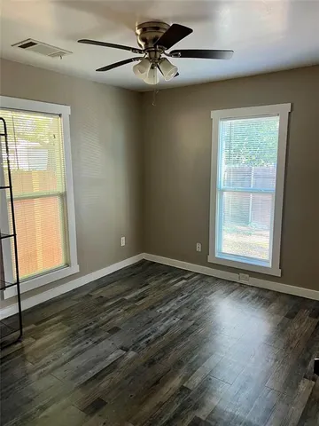 a view of an empty room with window and wooden floor