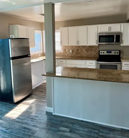 a kitchen with granite countertop a refrigerator and a stove top oven