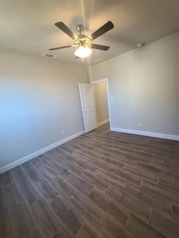 an empty room with wooden floor fan and windows