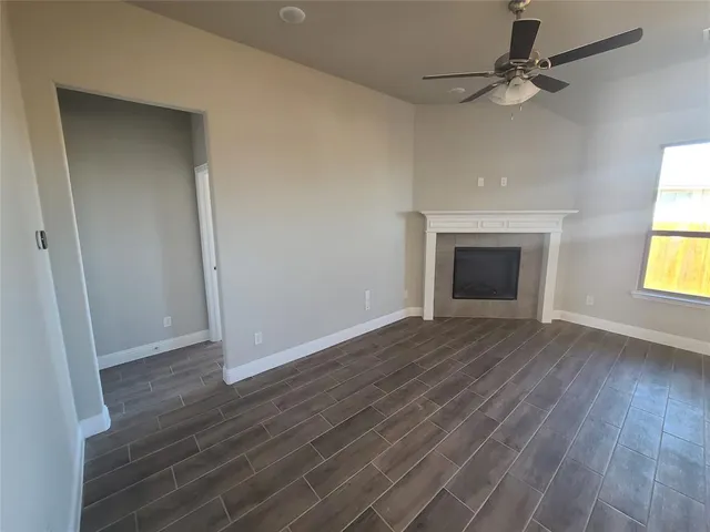 an empty room with wooden floor fireplace and windows