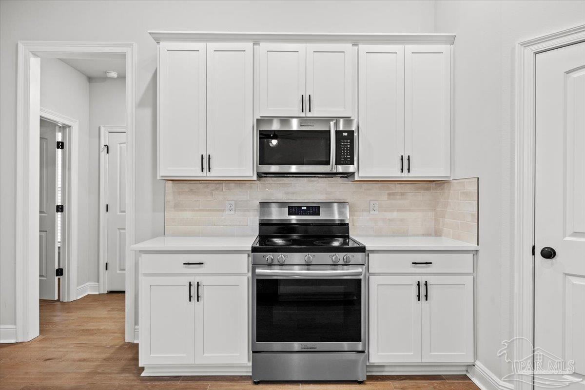 5362 Adeline Circle Pace, FL 32571 - Photo 13 of 40 a kitchen with stainless steel appliances granite countertop white cabinets and a stove top oven