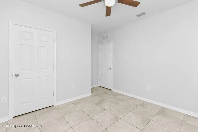 an empty room with chandelier fan