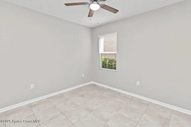 an empty room with windows and chandelier fan