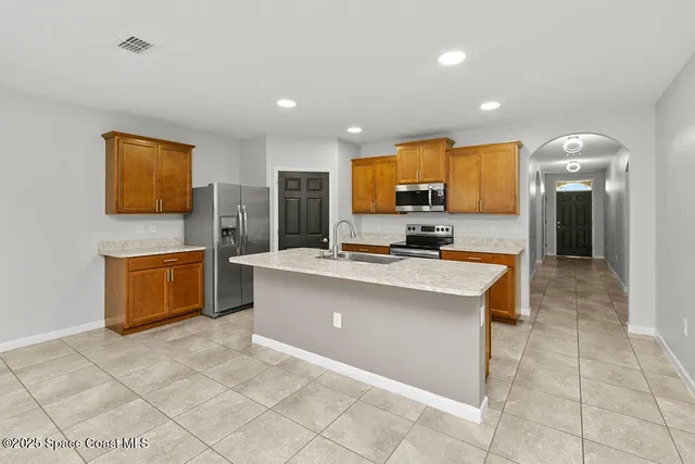 a large kitchen with stainless steel appliances a stove a sink a counter top space and cabinets
