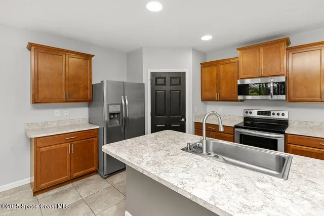 a kitchen with stainless steel appliances kitchen island granite countertop a sink stove and refrigerator