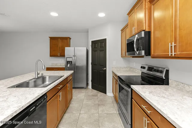 a kitchen with stainless steel appliances granite countertop a sink a stove and a refrigerator