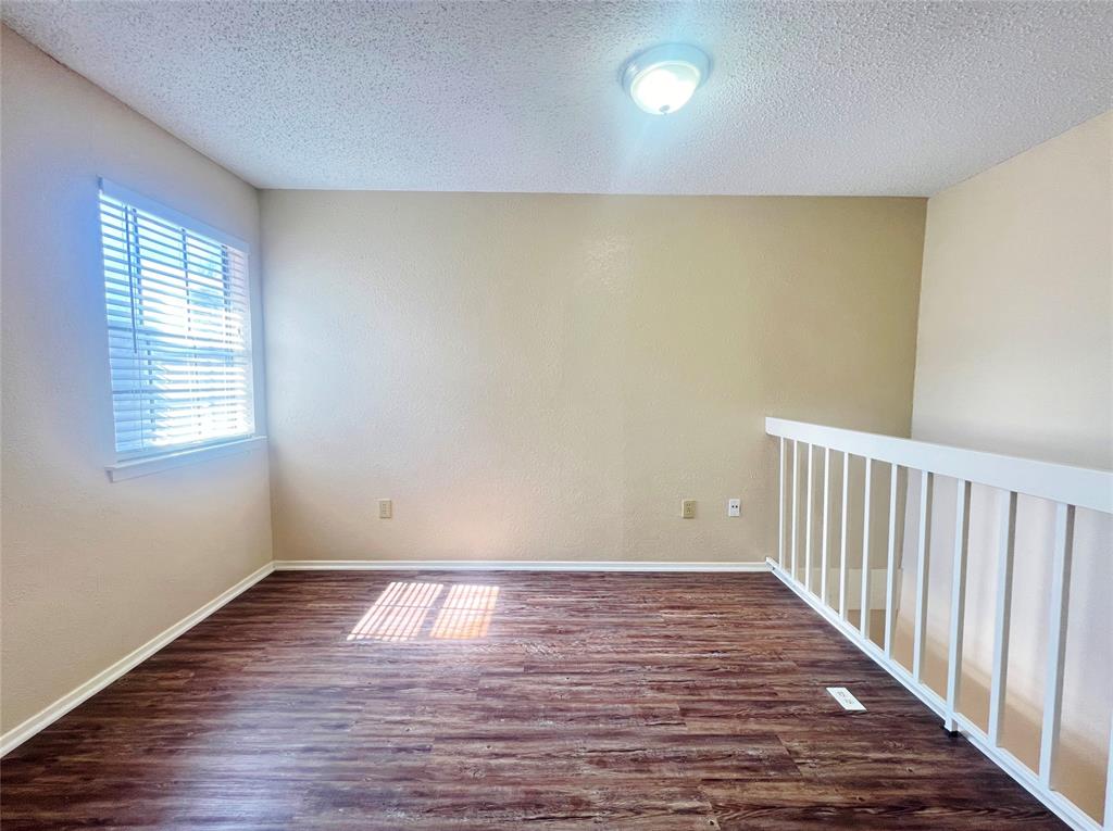 5626 Preston Oaks Road, Unit 43D Dallas, TX 75254 - Photo 7 of 9 a view of an empty room with wooden floor and a window