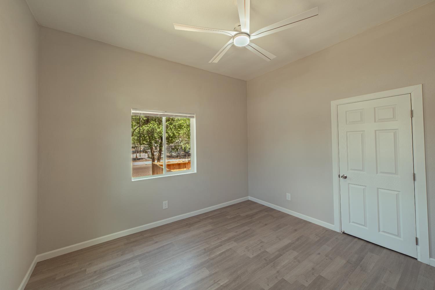 2320 K Street Merced, CA 95340 - Photo 13 of 25 an empty room with wooden floor ceiling fan and windows