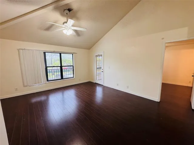 an empty room with wooden floor chandelier fan and windows