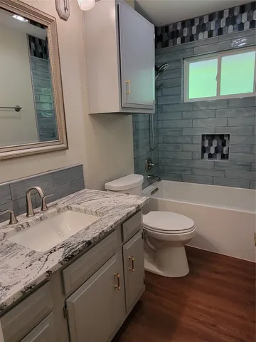 a bathroom with a granite countertop toilet a sink and bathtub