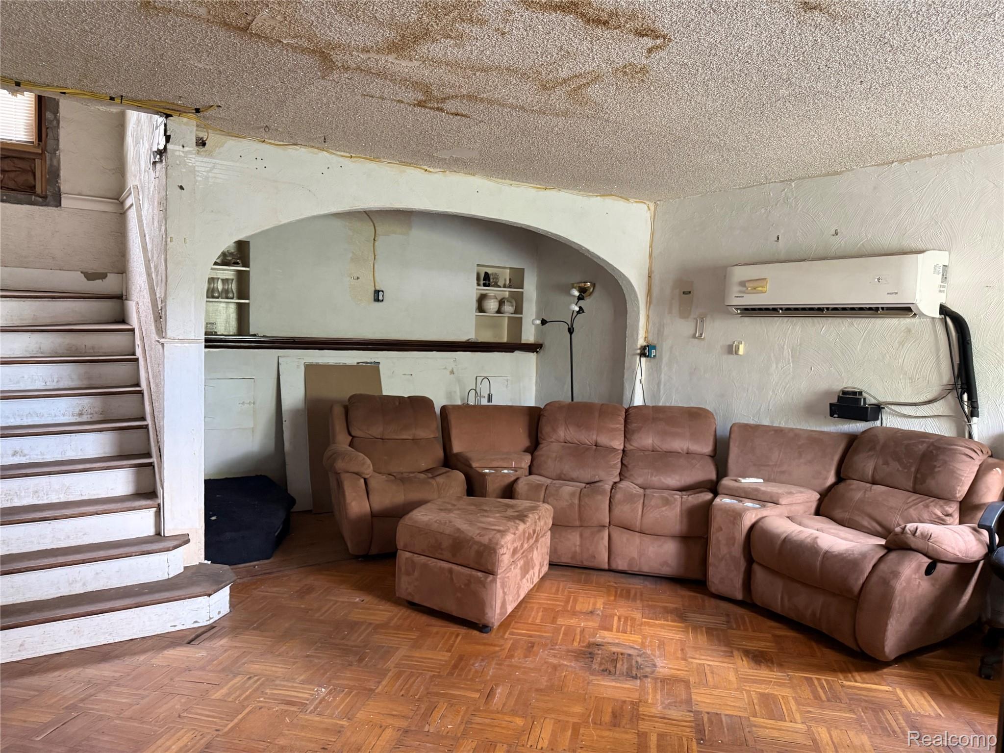 13276 Strathmoor Street Detroit, MI 48227 - Photo 4 of 13 Interior space featuring a built-in staircase with wood treads, parquet flooring, an arched opening with built-in shelving, and a wall-mounted air conditioning unit