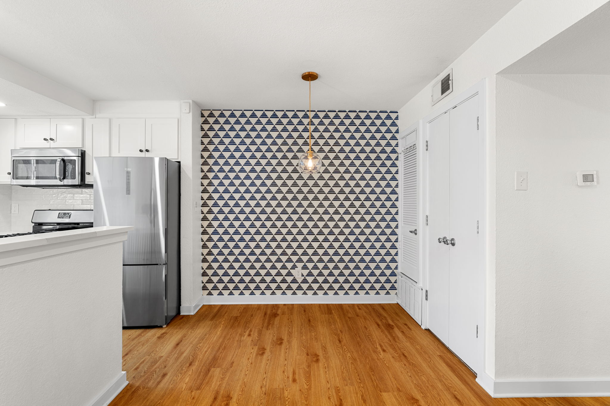 3601 Menchaca Road, Unit 110 Austin, TX 78704 - Photo 19 of 37 A dining area with lively geometric wallpaper and a clear glass pendant light.