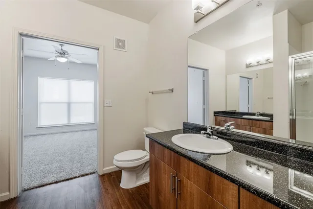 a bathroom with a granite countertop toilet a mirror and a sink