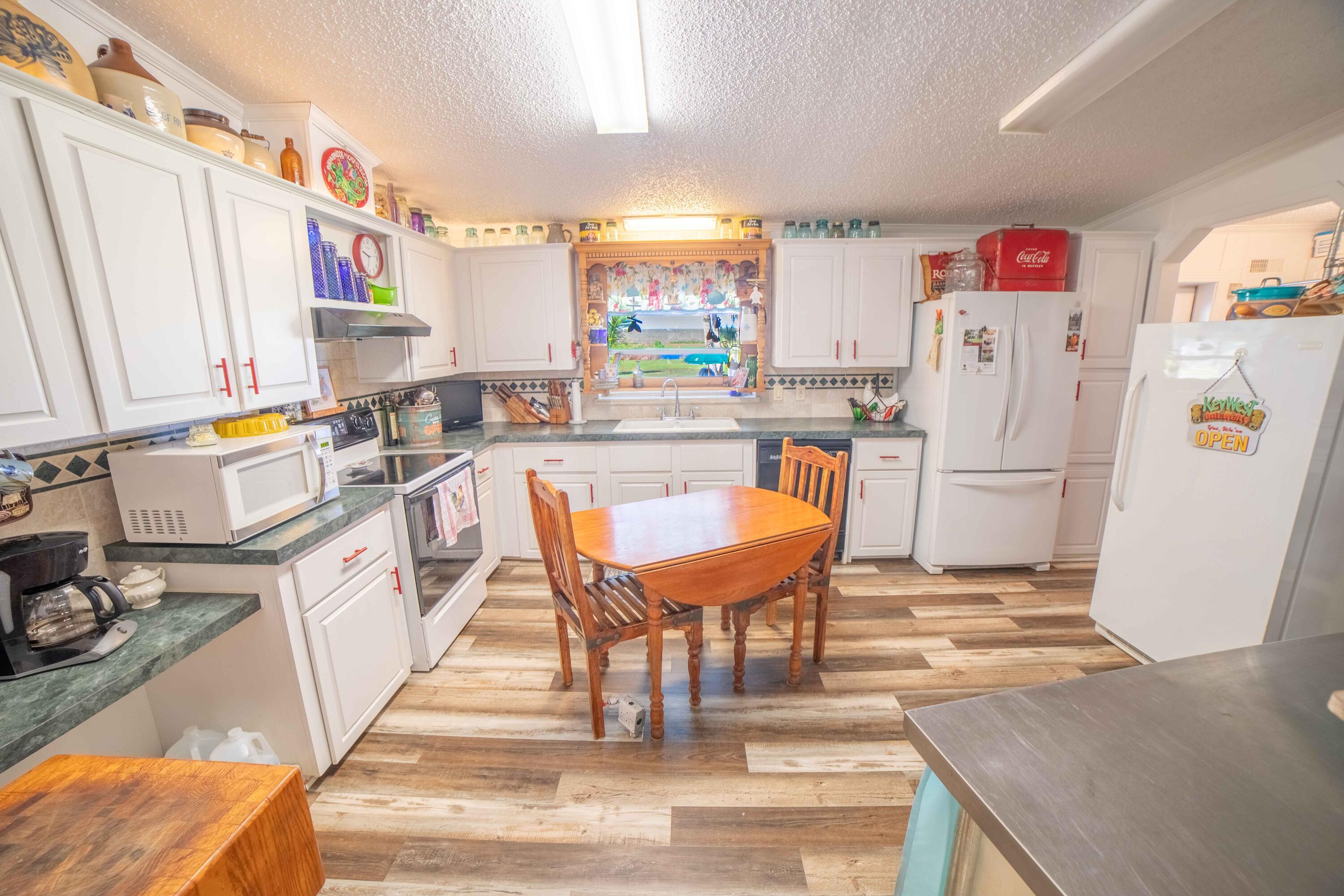 12302 Highway 441 Okeechobee, FL 34974 - Photo 19 of 63 a kitchen with stainless steel appliances granite countertop a refrigerator a sink dishwasher a stove and white countertops with wooden floor