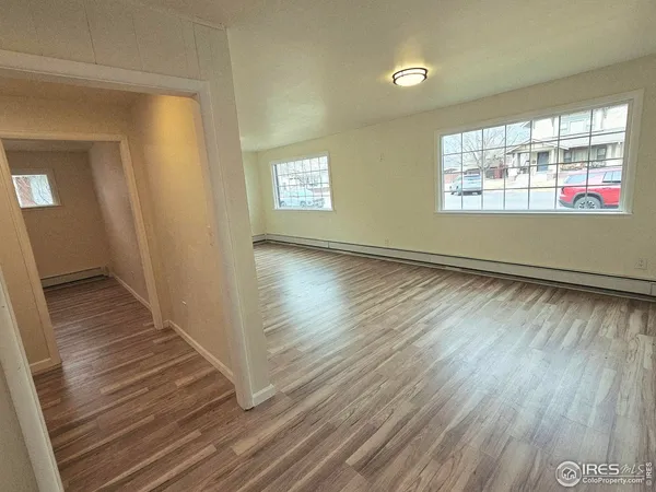 a view of an empty room with wooden floor and a window