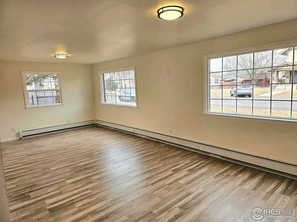 a view of kitchen and empty room with wooden floor