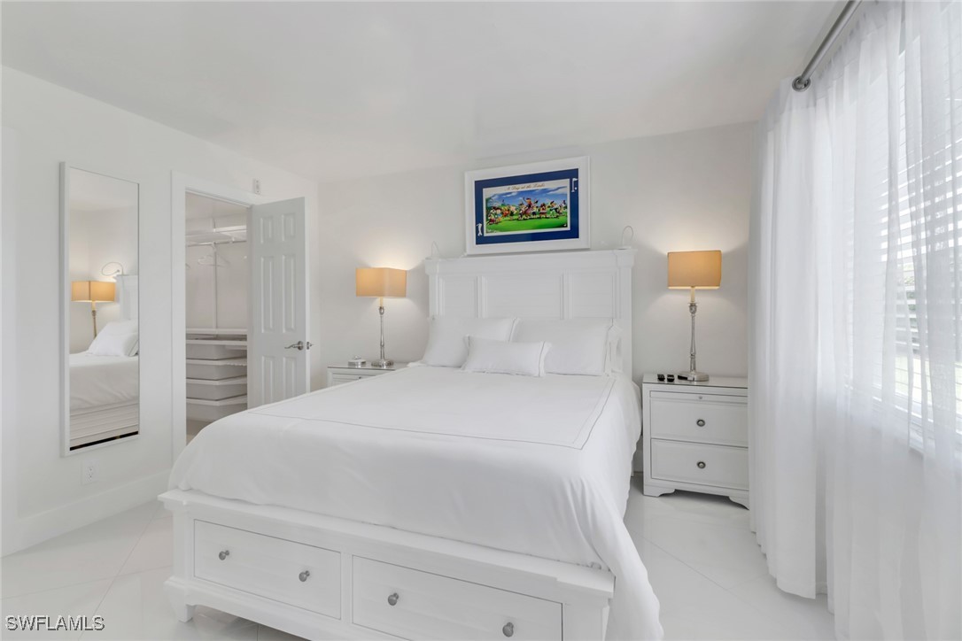 9 High Point Circle North, Unit 102 Naples, FL 34103 - Photo 14 of 48 a bedroom with a bed and a painting on the wall