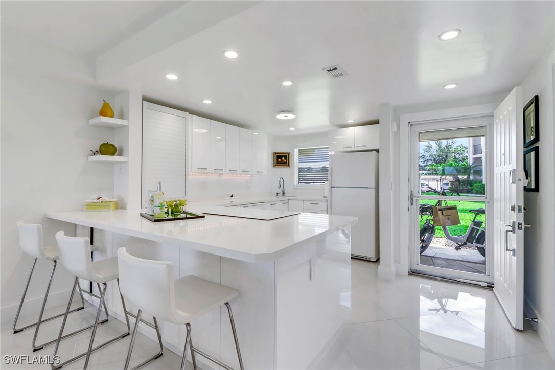 9 High Point Circle North, Unit 102 Naples, FL 34103 - Photo 2 of 48 a kitchen with kitchen island a counter top space a sink stainless steel appliances and cabinets