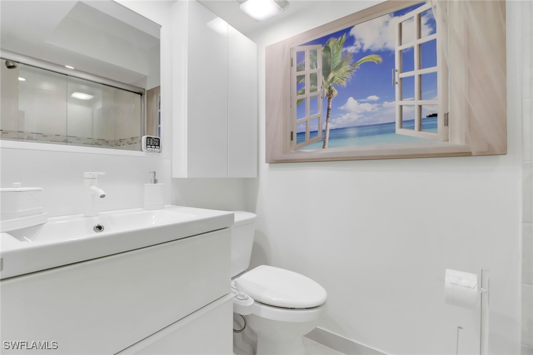 9 High Point Circle North, Unit 102 Naples, FL 34103 - Photo 22 of 48 a bathroom with a sink a mirror and a toilet