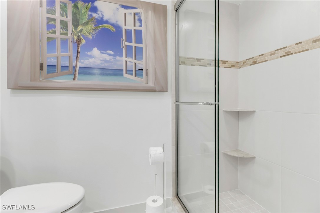 9 High Point Circle North, Unit 102 Naples, FL 34103 - Photo 23 of 48 a bathroom with a granite countertop shower and a toilet