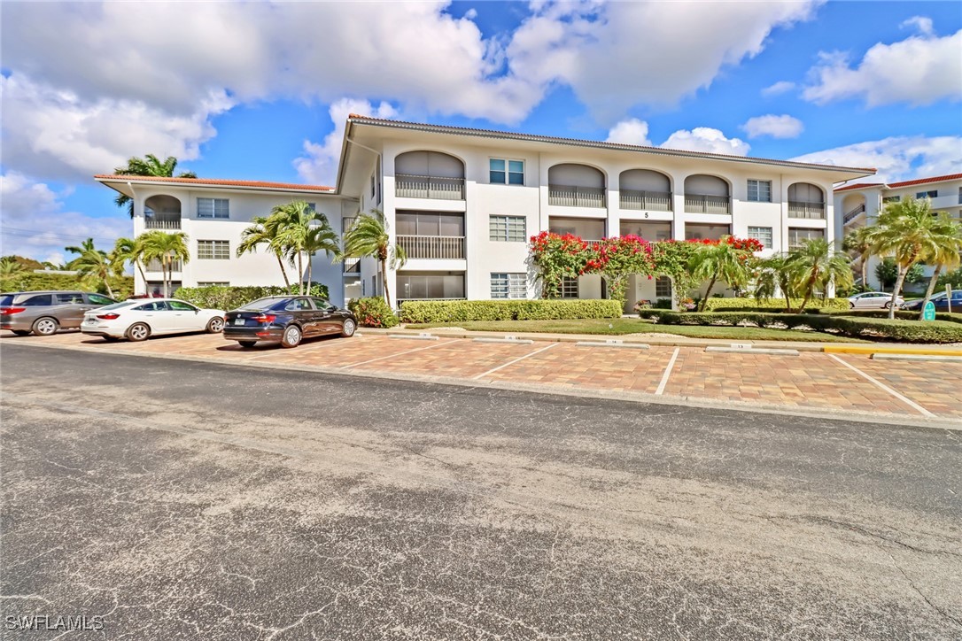 9 High Point Circle North, Unit 102 Naples, FL 34103 - Photo 26 of 48 a front view of a house with a yard and parking