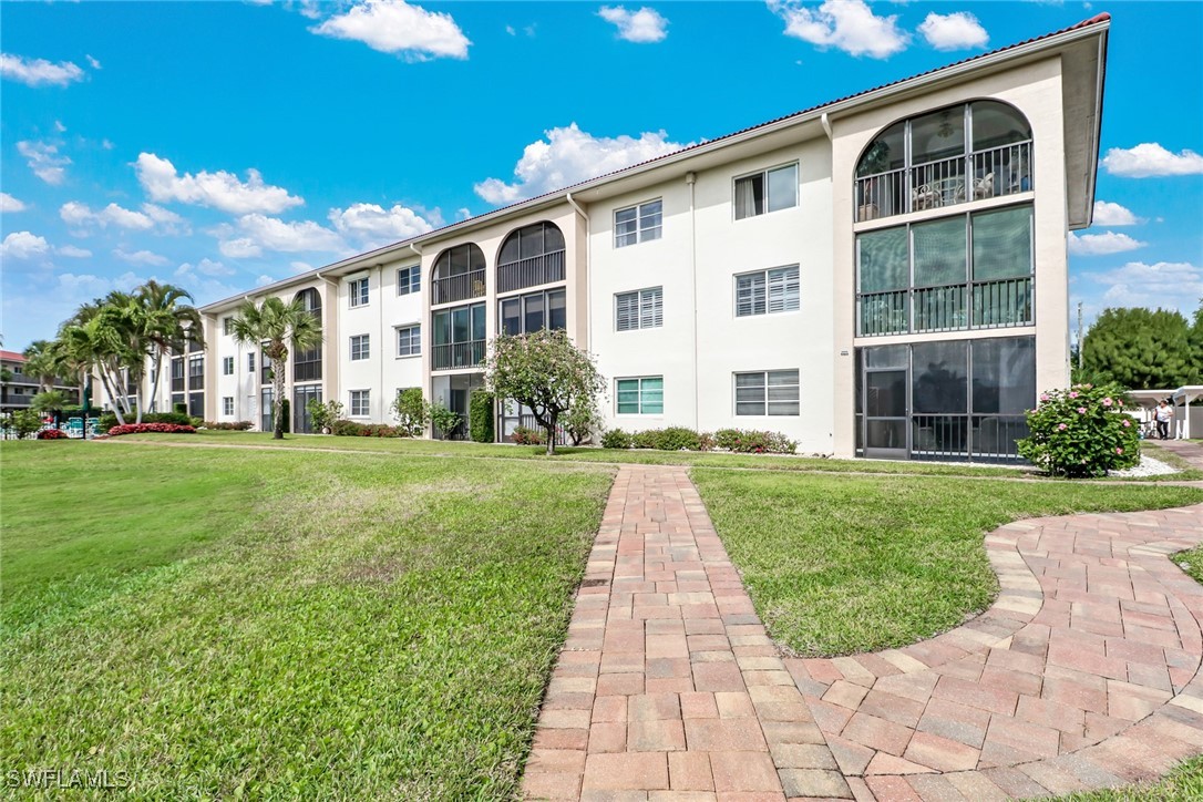 9 High Point Circle North, Unit 102 Naples, FL 34103 - Photo 38 of 48 a front view of a house with a yard