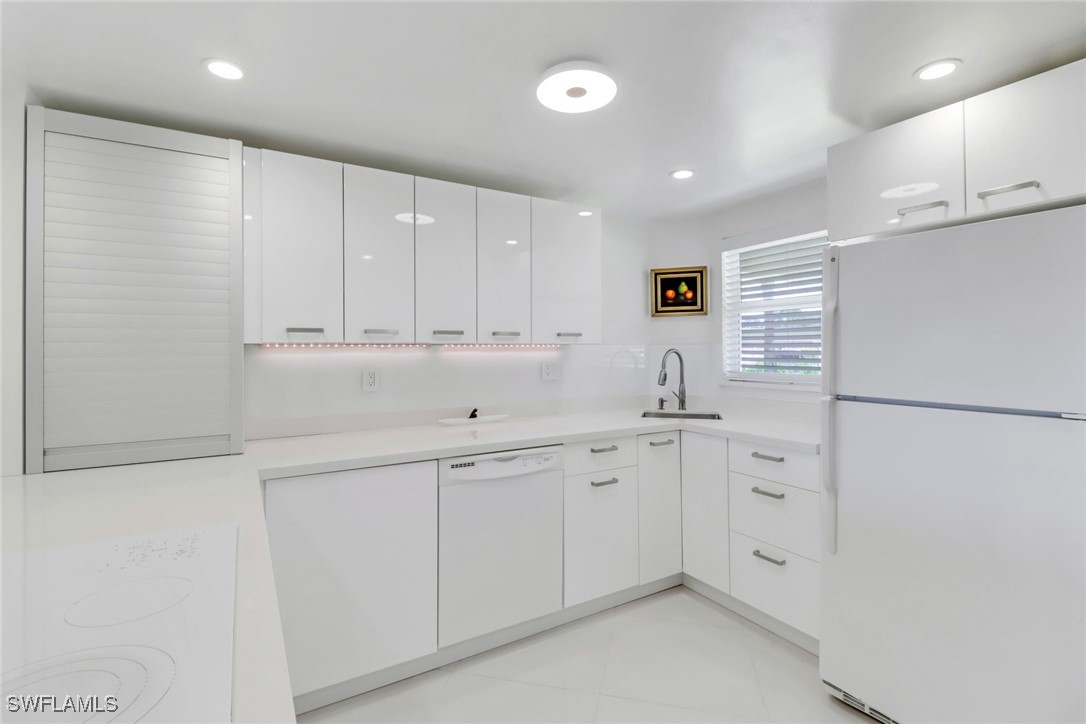 9 High Point Circle North, Unit 102 Naples, FL 34103 - Photo 5 of 48 a kitchen with white cabinets and sink