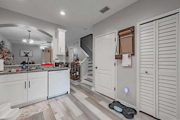 a large white kitchen with a sink and dishwasher a stove with wooden floor