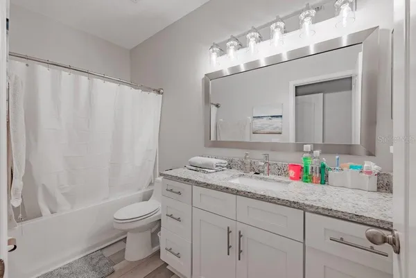 a bathroom with a granite countertop sink a toilet and a mirror
