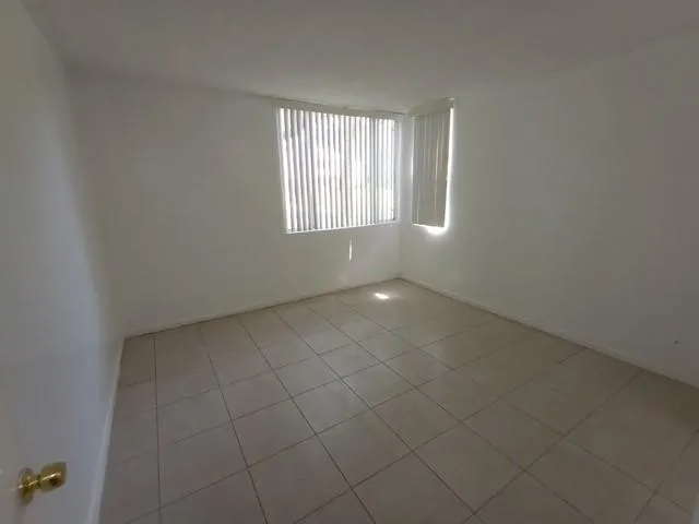 an empty room with mirror and a bathroom