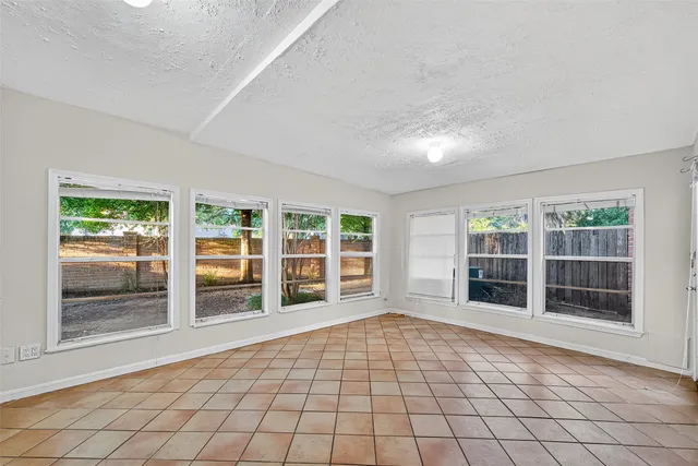 an empty room with wooden floor ceiling fan and windows