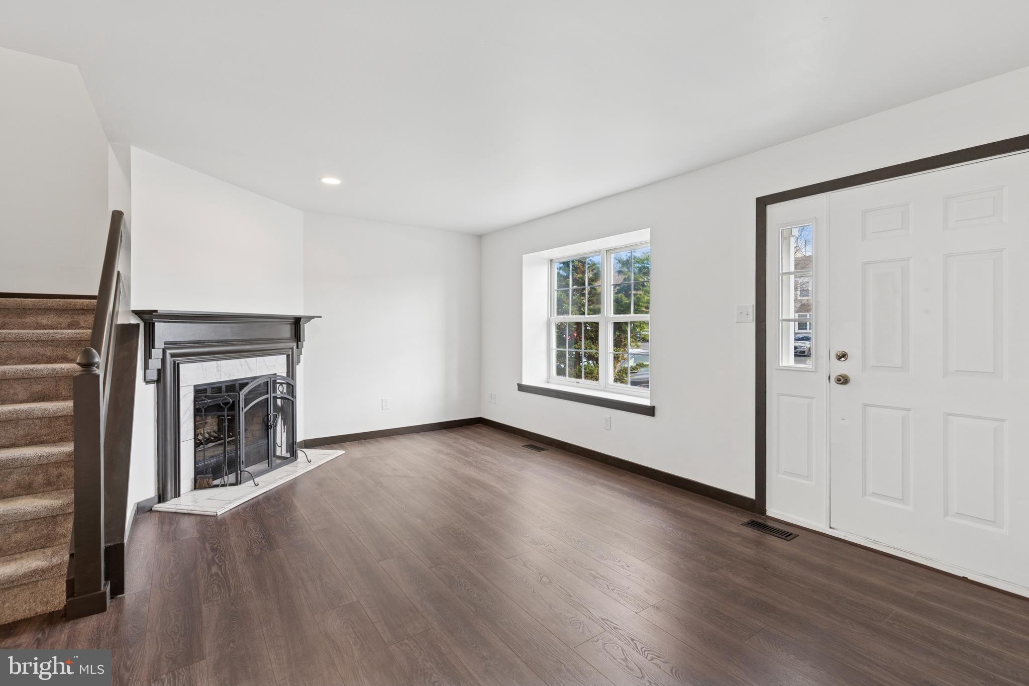615 Longwood Road Collegeville, PA 19426 - Photo 6 of 25 an empty room with wooden floor fireplace and windows