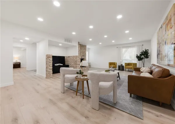 a living room with furniture a view of kitchen and a flat screen tv