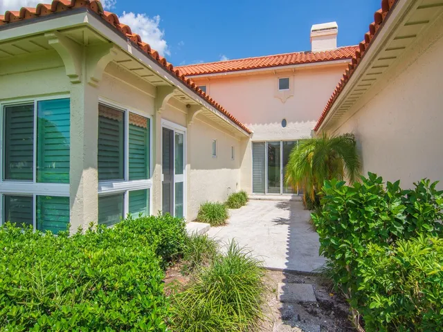 a view of a white house with potted plants and a table