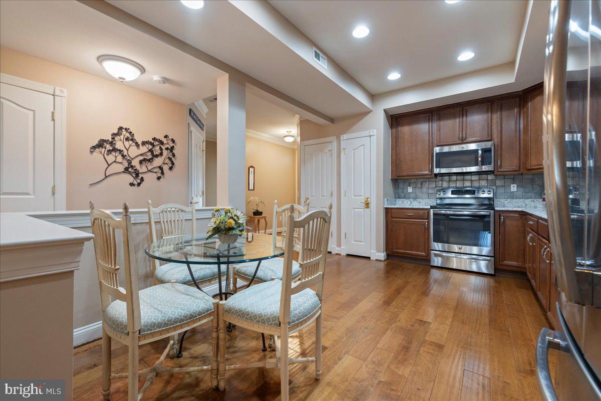 327 Melbourne Way Souderton, PA 18964 - Photo 12 of 44 a kitchen with stainless steel appliances kitchen island granite countertop a stove a refrigerator a sink a dining table and chairs with wooden floor