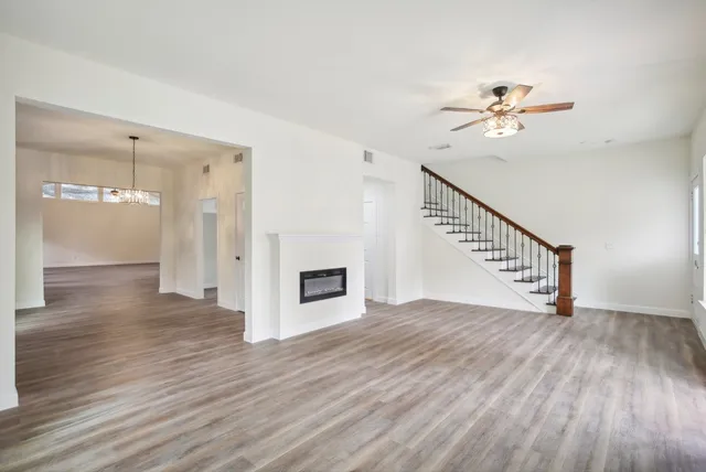 a view of empty room with wooden floor and ceiling fan