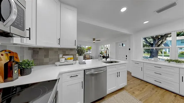 a kitchen with stainless steel appliances white cabinets and wooden floors