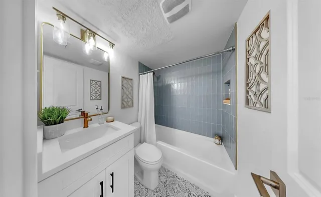 a bathroom with a granite countertop sink a toilet a mirror a bathtub and shower