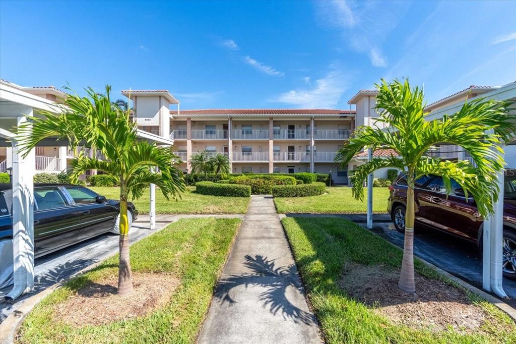 6505 Stone River Road, Unit 202 Bradenton, FL 34203 - Photo 1 of 55 a front view of a house with a yard and potted plants