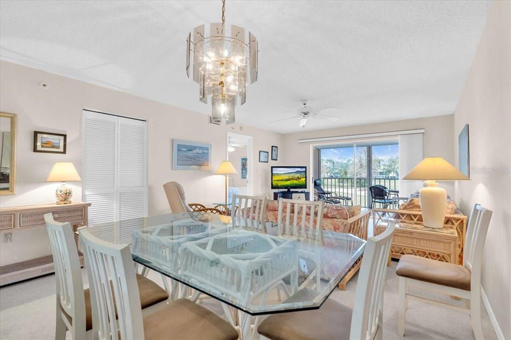 6505 Stone River Road, Unit 202 Bradenton, FL 34203 - Photo 18 of 55 a view of a dining room with furniture a chandelier and wooden floor
