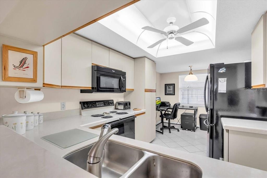 6505 Stone River Road, Unit 202 Bradenton, FL 34203 - Photo 8 of 55 a kitchen with a refrigerator a sink and chairs