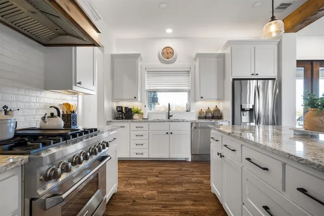 a kitchen with stainless steel appliances granite countertop a stove a sink and a refrigerator