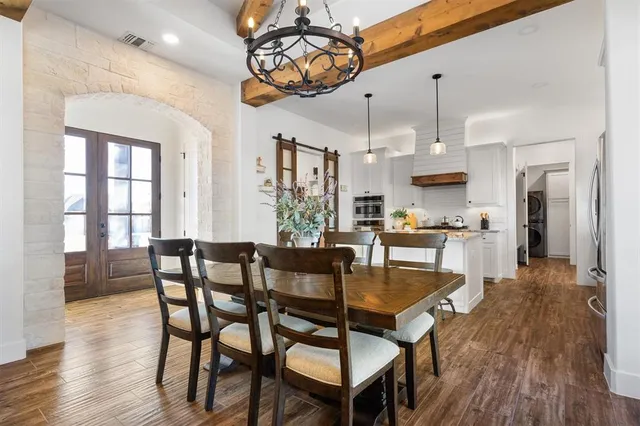a view of a dining room and livingroom with furniture wooden floor kitchen chandelier