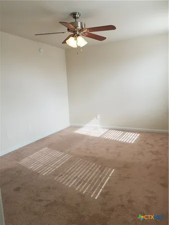 an empty room with a window and a fan