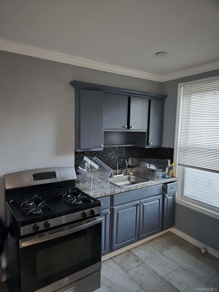 515 Summit Avenue Schenectady, NY 12307 - Photo 10 of 15 Kitchen featuring gas stove, gray cabinets, crown molding, decorative backsplash, and dark stone counters