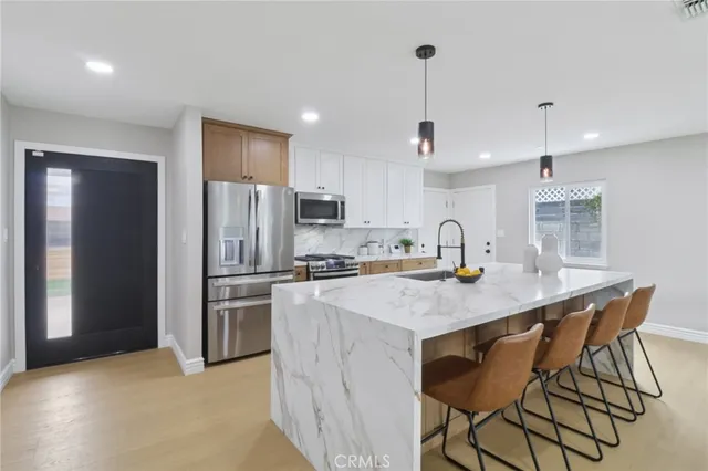 a kitchen with stainless steel appliances granite countertop a sink a stove a refrigerator and island with wooden floor