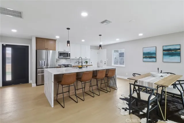 a kitchen with kitchen island a dining table chairs stainless steel appliances and cabinets
