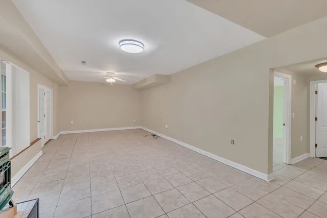 a view of an empty room with a fireplace and a ceiling fan