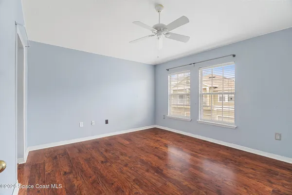 a view of empty room with wooden floor and fan