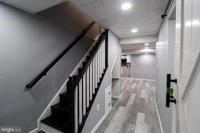 a view of staircase with lots of frames on wall and wooden floor